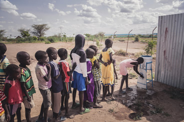 A group of refugee children queuing up for clean drinking water