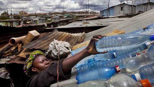A lady placing bottles of clear water laid on a roof for solar disinfection to remove contamination from water