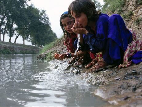 Two kids drinking water from polluted source