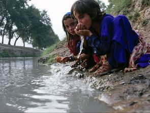 Two kids drinking water from polluted water source