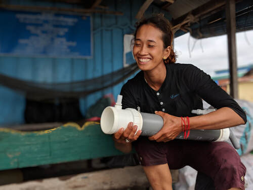 A lady smiling while holding on to a life saving water filter called the ROAMfilter Plus 