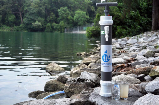 A portable water filtration system, ROAMfilter Plus next to a contaminated water source 