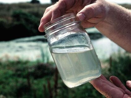 A jar filled with contaminated water colelcted from an unimproved and dirty water source
