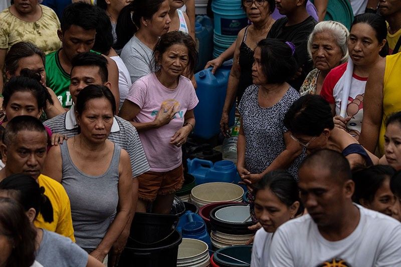 A crowd of Filipino residents waiting in line to receive clean and safe water distributed on water tank truck and fire trucks