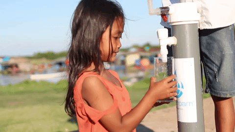 A young girl obtaining safe drinking water using Wateroam's portable water filter called the ROAMfilter Plus